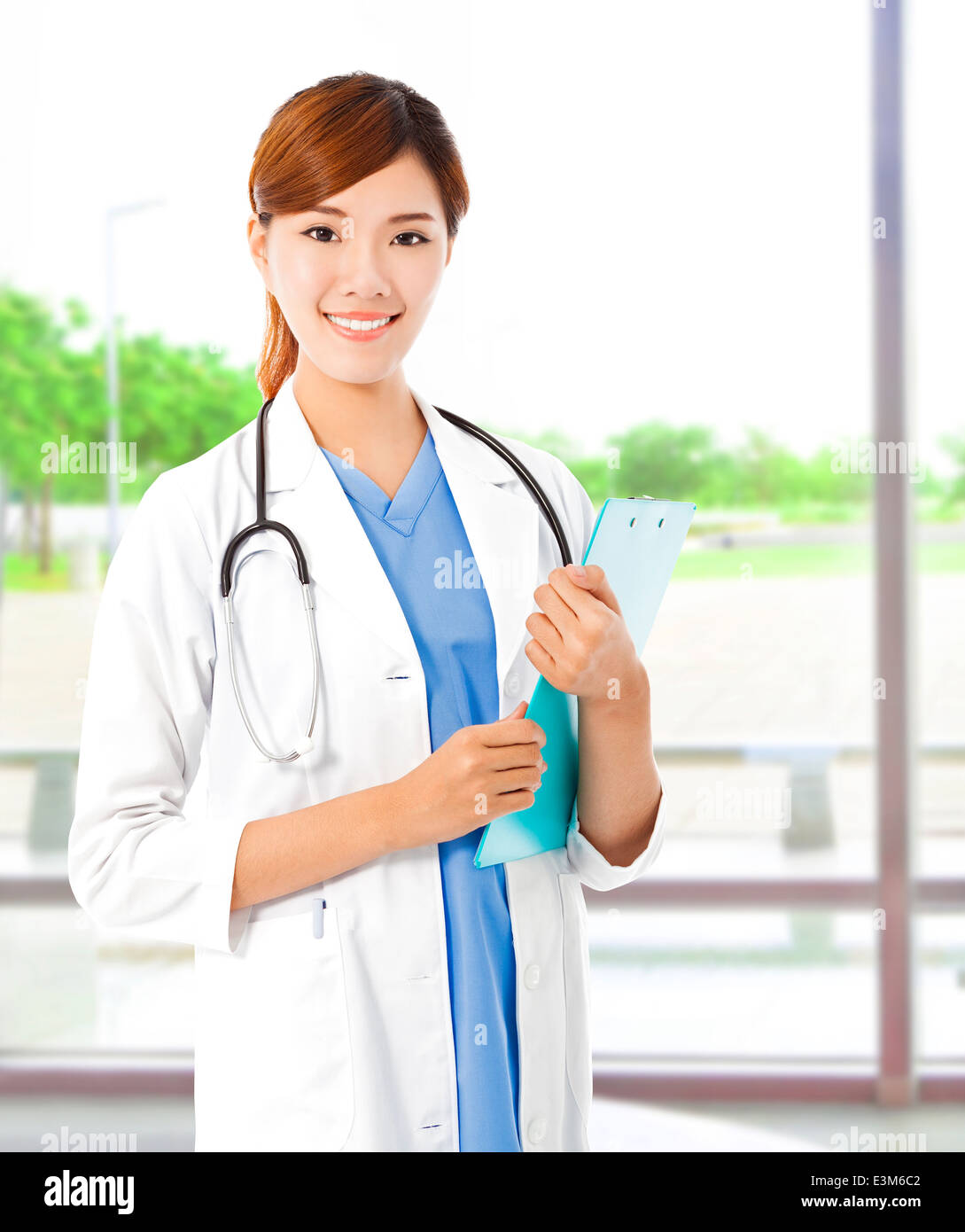 Pretty young female doctor standing and holding document Stock Photo