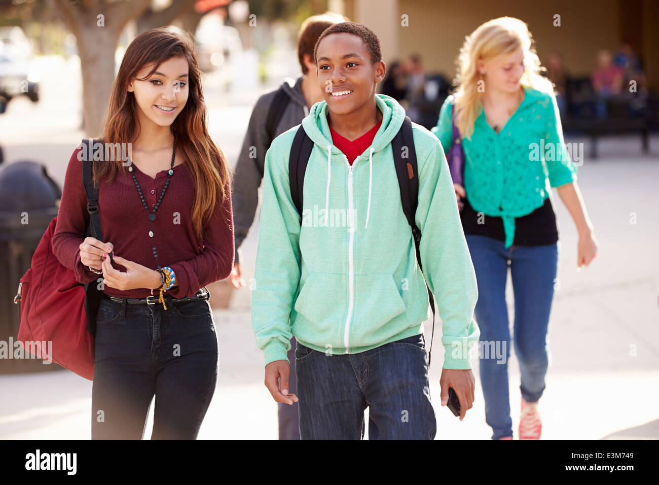 Male And Female Students Walking To High School Stock Photo