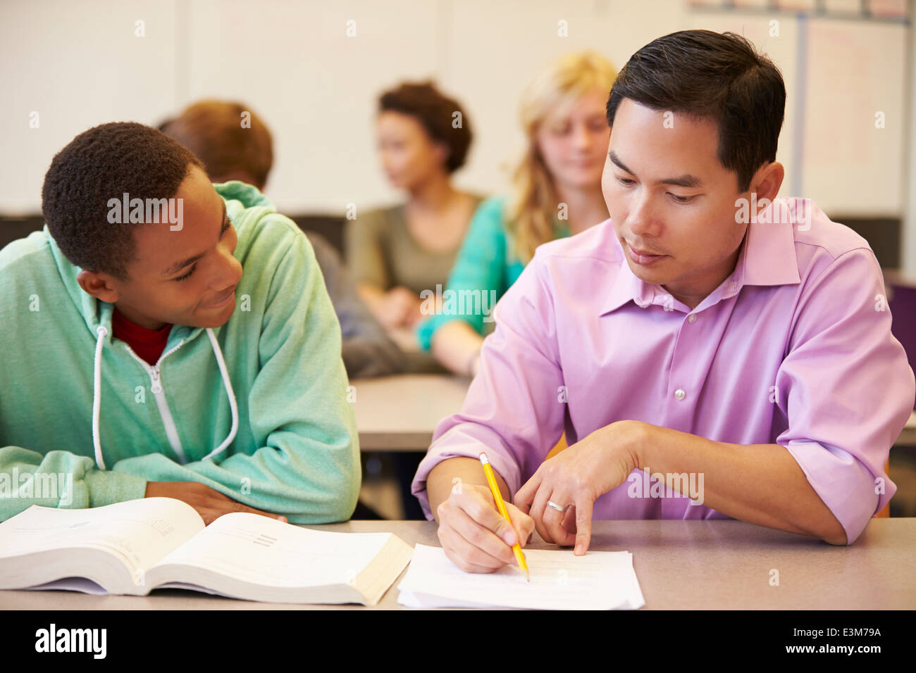 High School Teacher Helping Student With Written Work Stock Photo