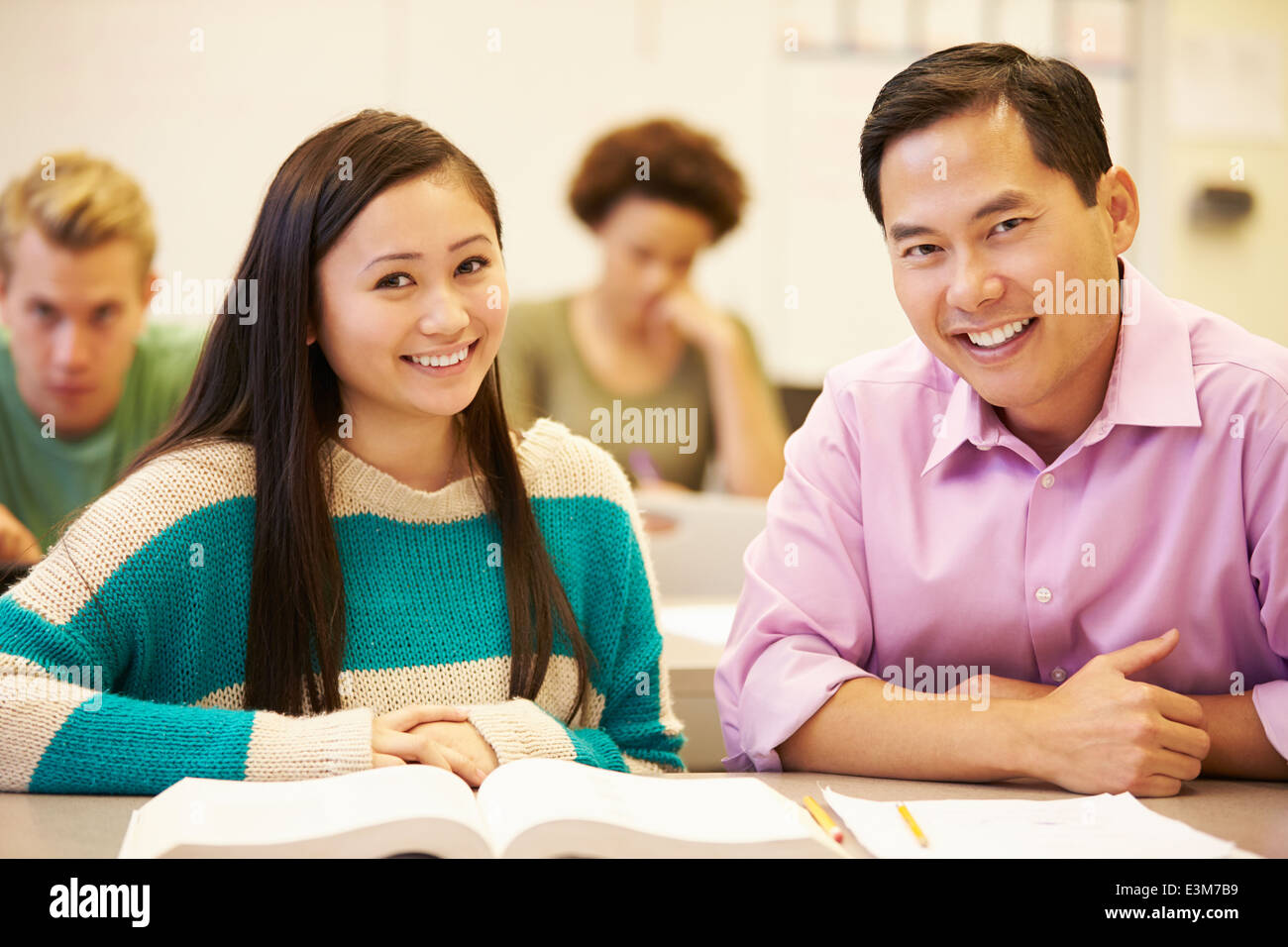 Female High School Student With Teacher Studying At Desk Stock Photo