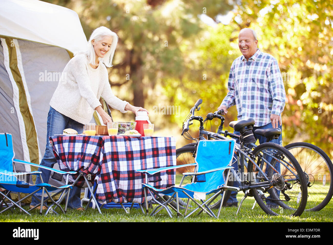 Senior Couple Riding Bikes On Camping Holiday In Countryside Stock Photo