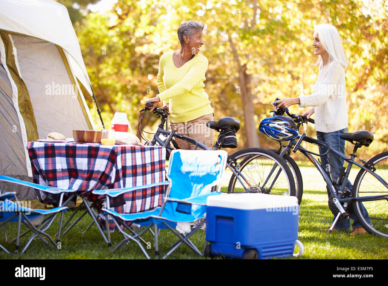 Two Mature Women Riding Bikes On Camping Holiday Stock Photo