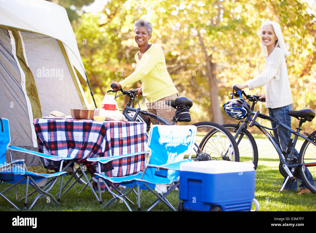 Two Mature Women Riding Bikes On Camping Holiday Stock Photo