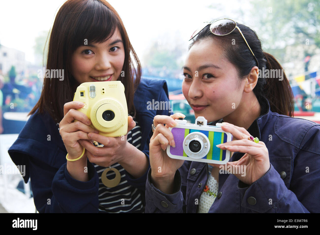 Two Asian female young adults holding retro camera cameras. People with cameras. Stock Photo