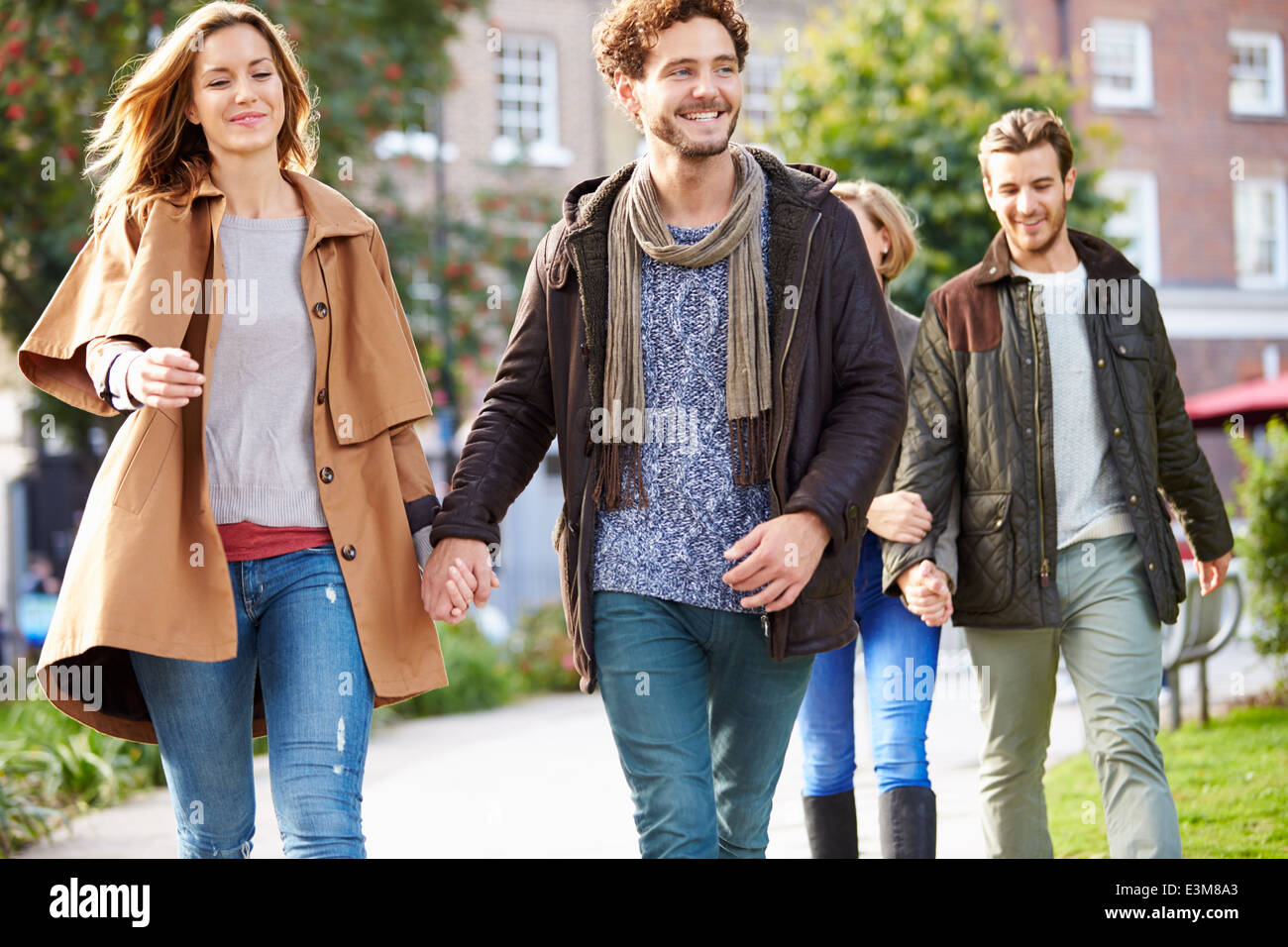 Group Of Friends Walking Through City Park Together Stock Photo