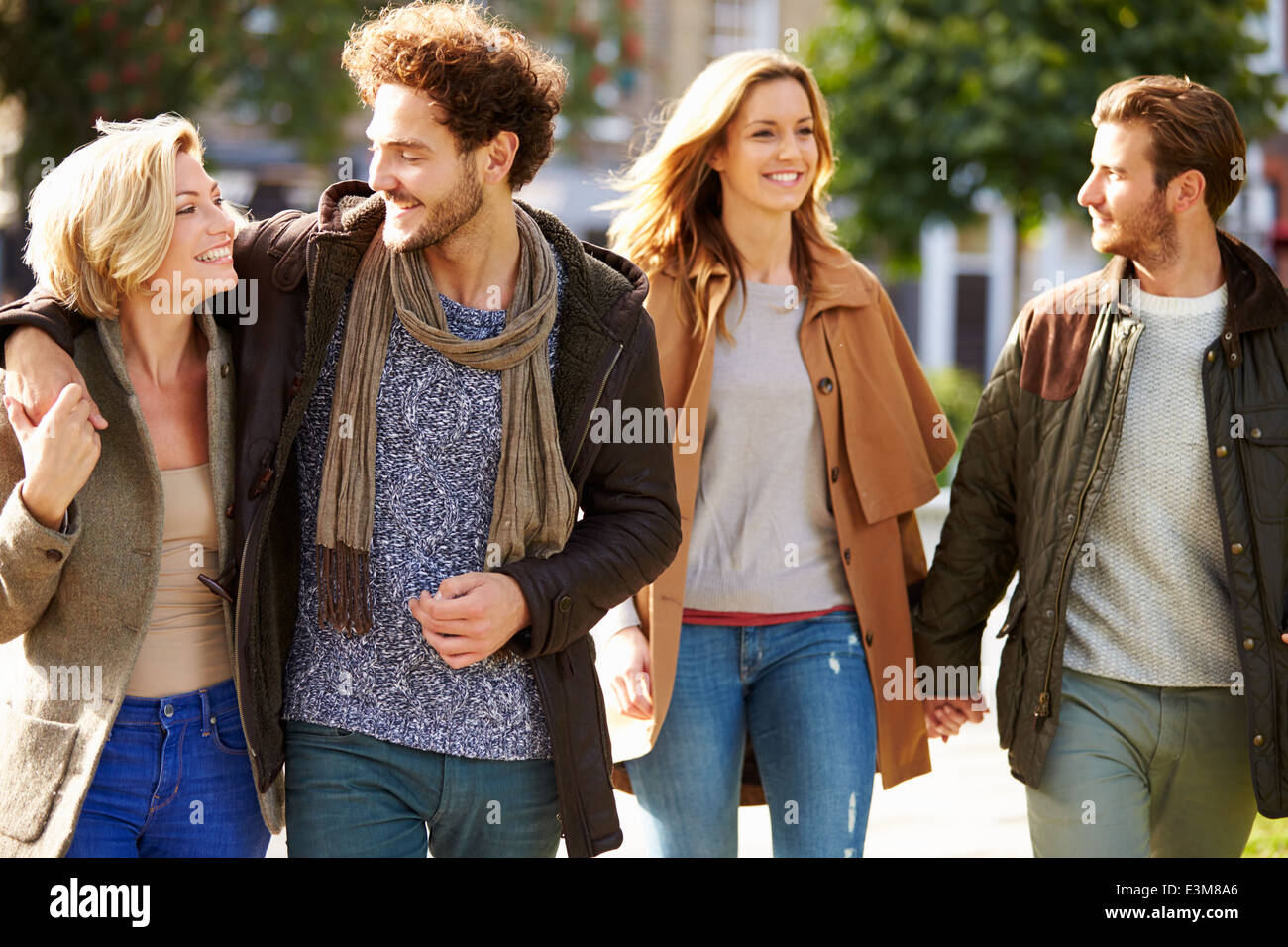 Group Of Friends Walking Through City Park Together Stock Photo