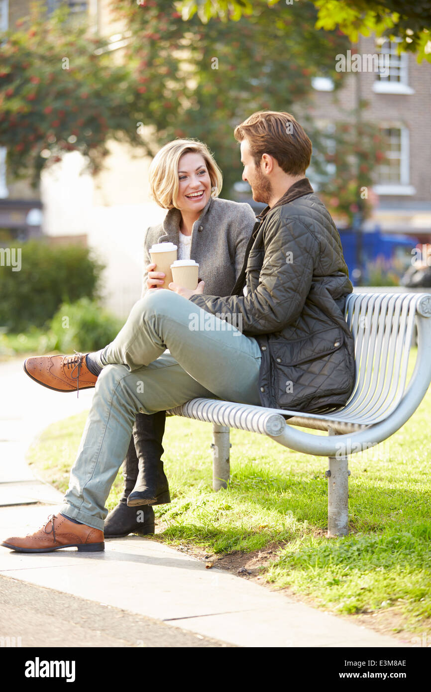 Couple Relaxing On Park Bench With Takeaway Coffee Stock Photo - Alamy