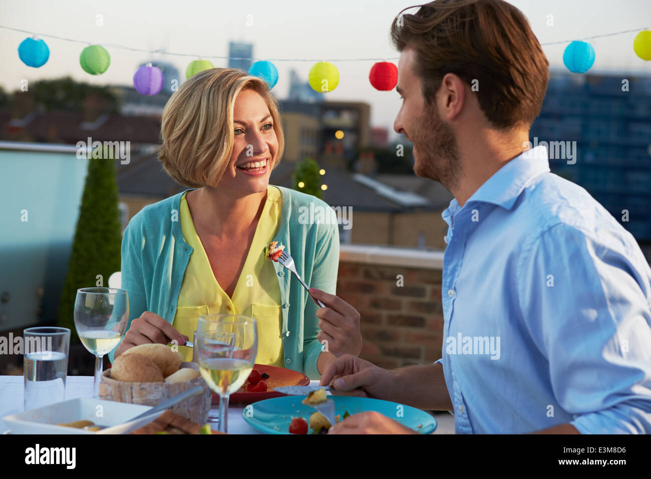 Couple Eating Evening Meal On Rooftop Terrace Stock Photo