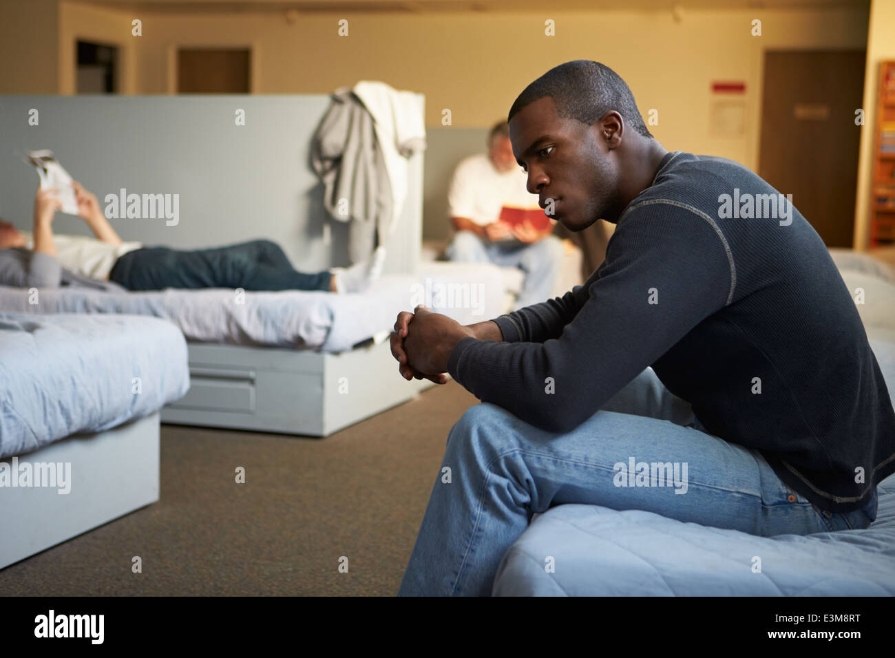 Men Sitting On Beds In Homeless Shelter Stock Photo