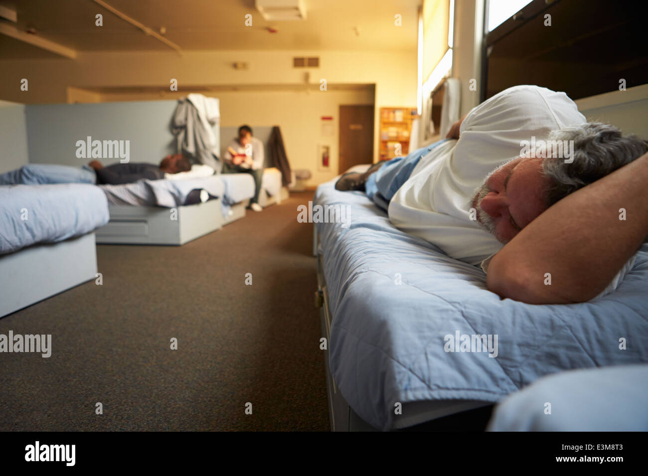 Men Lying On Beds In Homeless Shelter Stock Photo