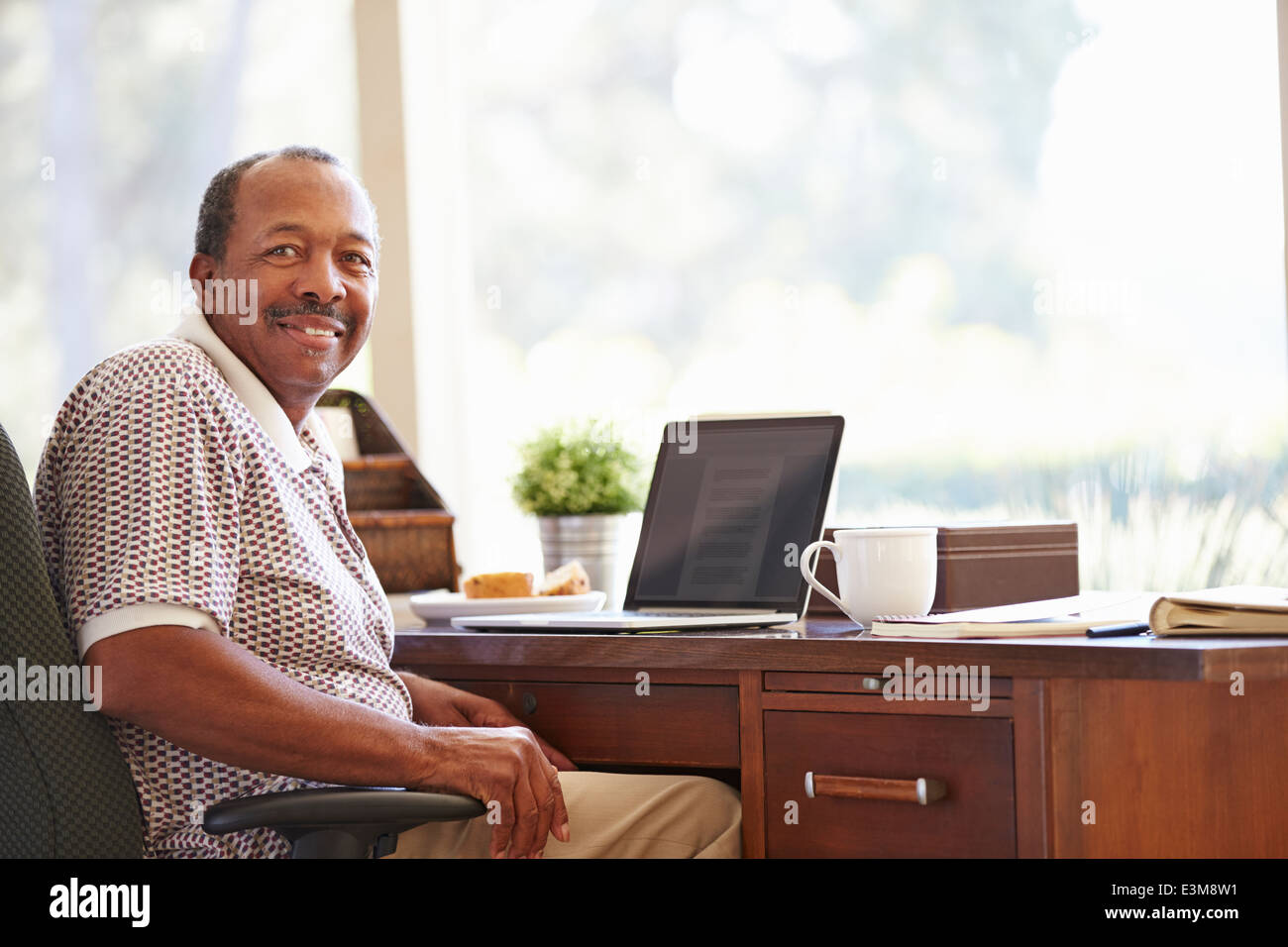 Senior Man Using Laptop On Desk At Home Stock Photo