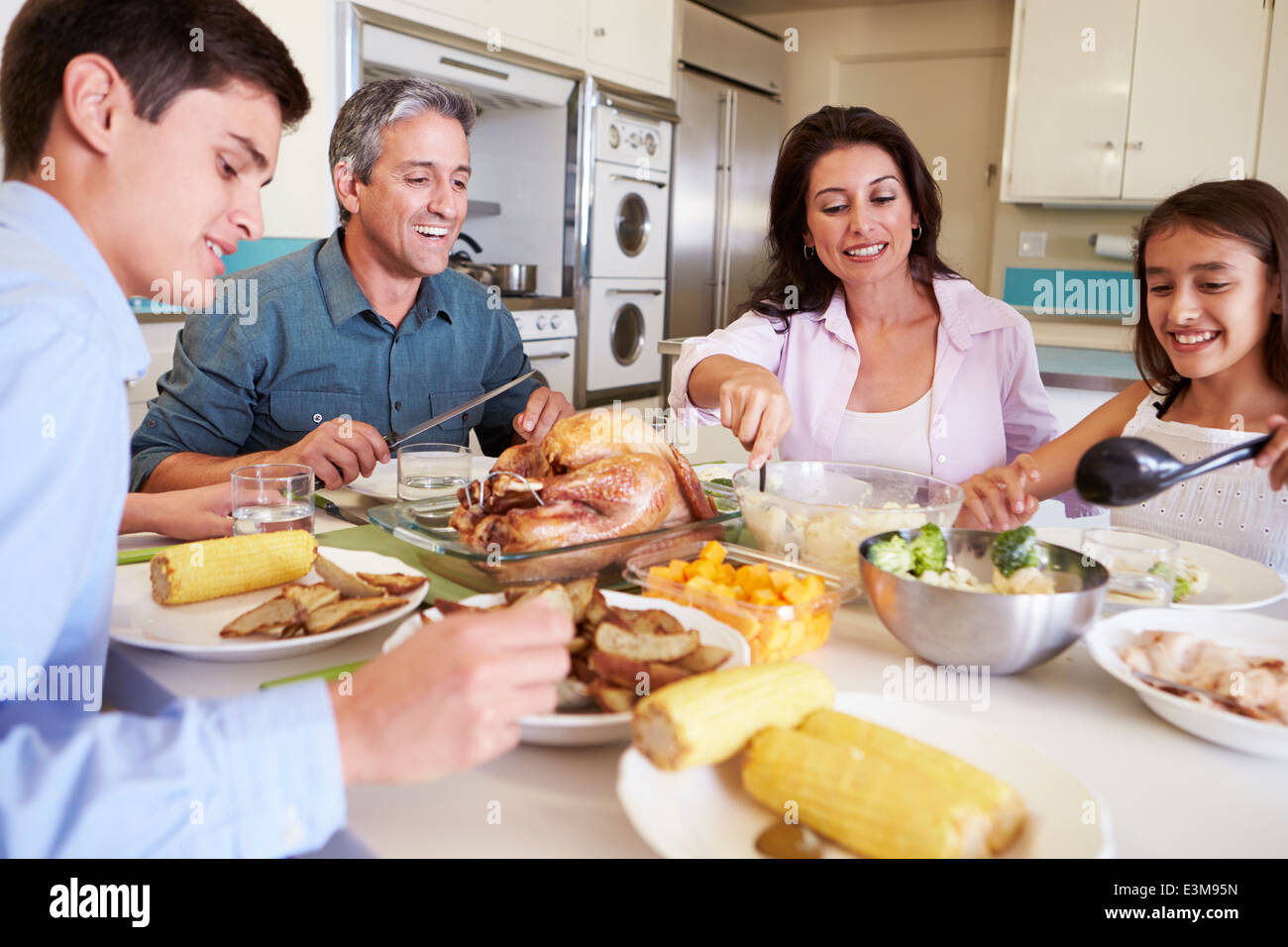 Family Sitting Around Table At Home Eating Meal Stock Photo