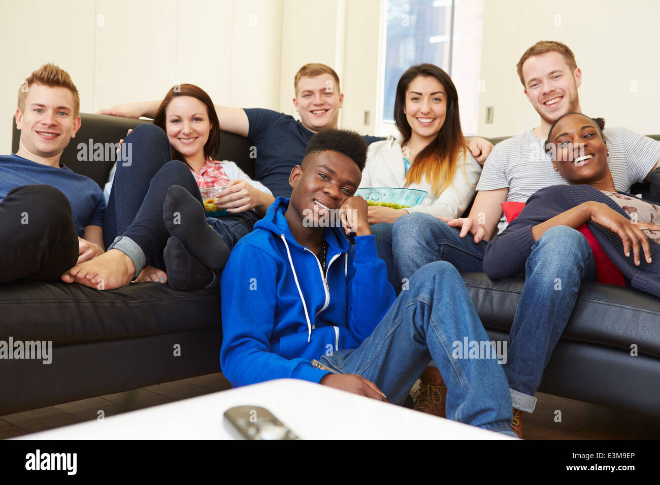 Group Of Friends Watching Television At Home Together Stock Photo