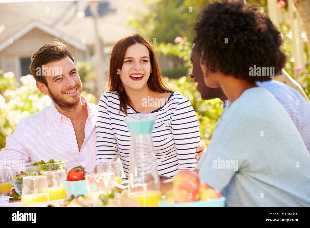 Group Of Friends Enjoying Meal At Outdoor Party In Back Yard Stock Photo