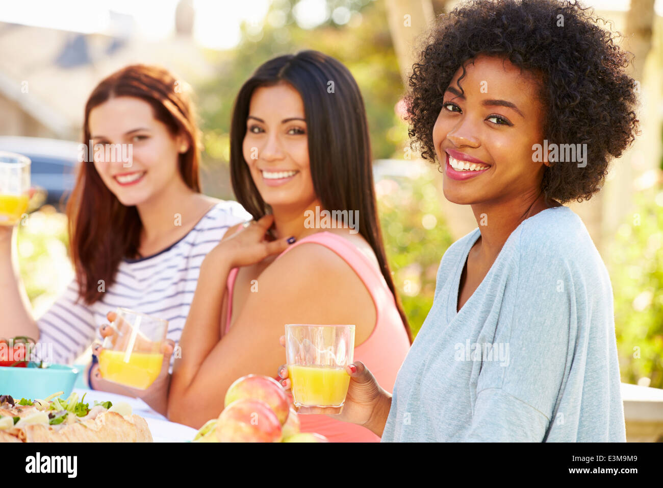 Three Female Friends Enjoying Meal At Outdoor Party Stock Photo