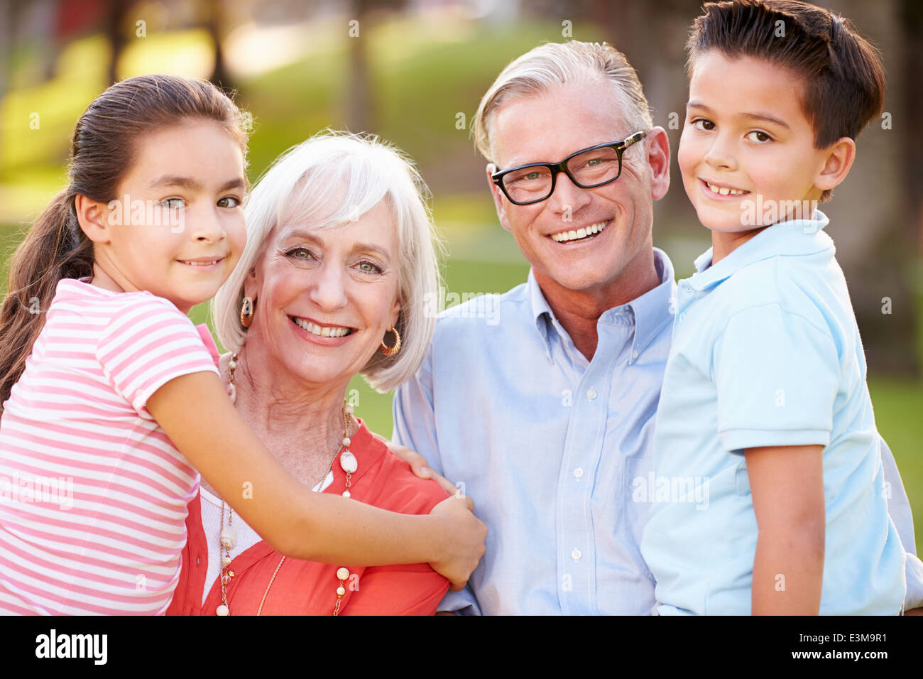 Outdoor Portrait Of Grandparents With Grandchildren In Park Stock Photo