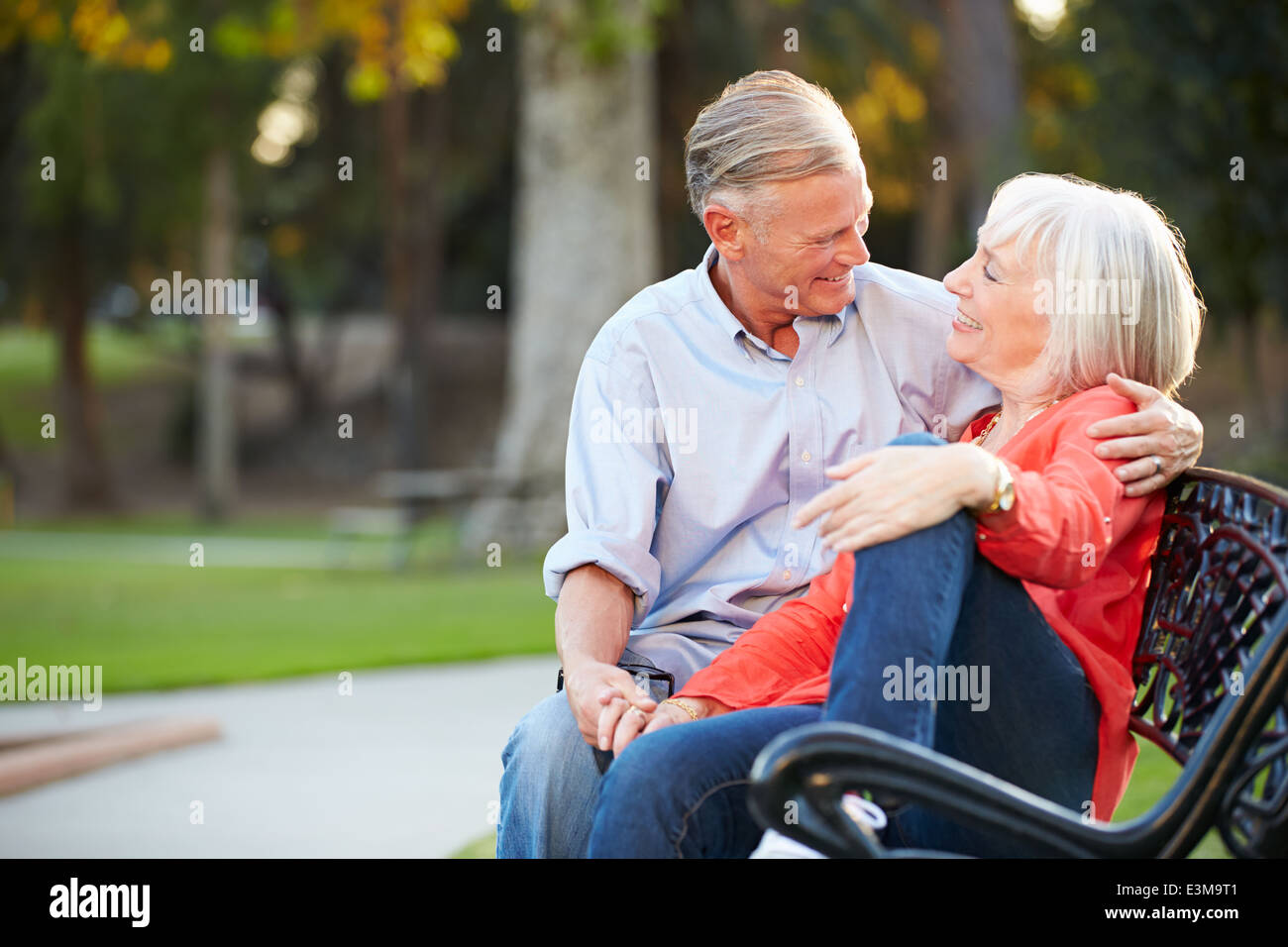 Mature Romantic Couple Sitting On Park Bench Together Stock Photo - Alamy