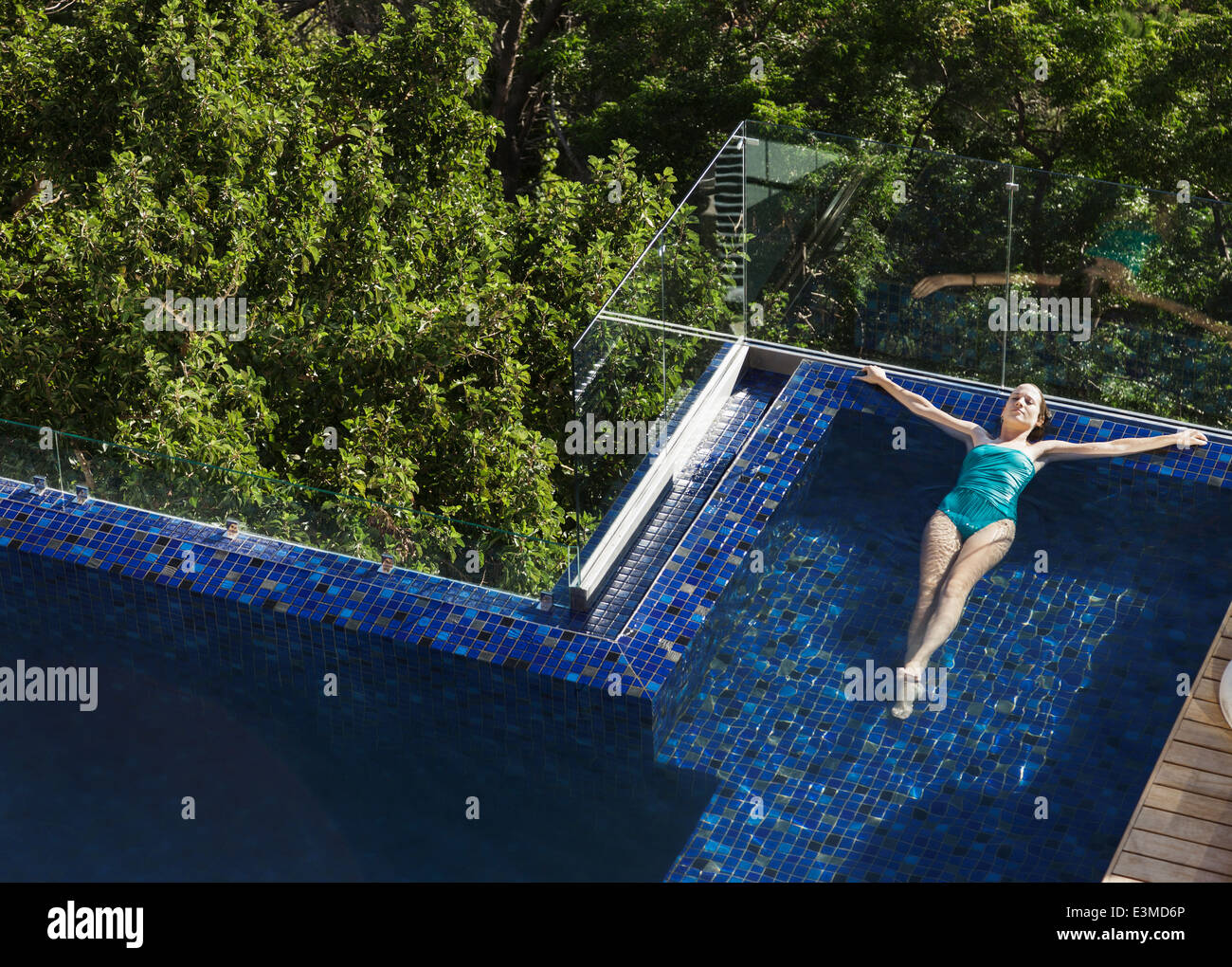 Woman floating in luxury swimming pool Stock Photo