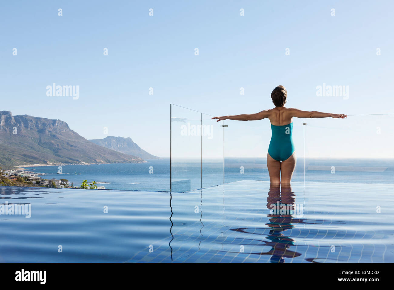 Woman basking in infinity pool overlooking ocean Stock Photo