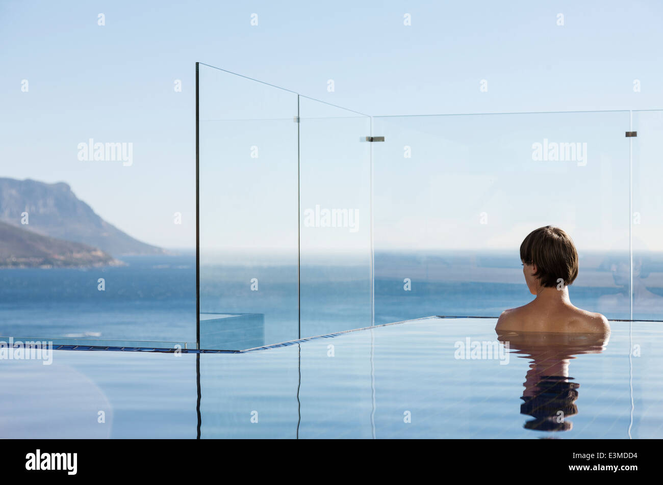 Woman in infinity pool enjoying ocean view Stock Photo