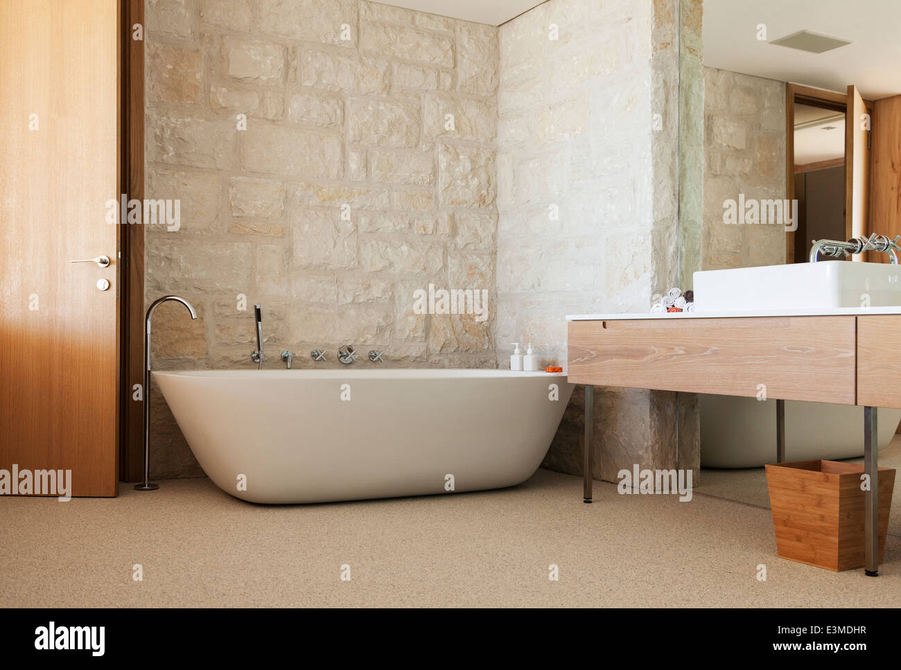 Stone wall behind soaking tub in modern bathroom Stock Photo