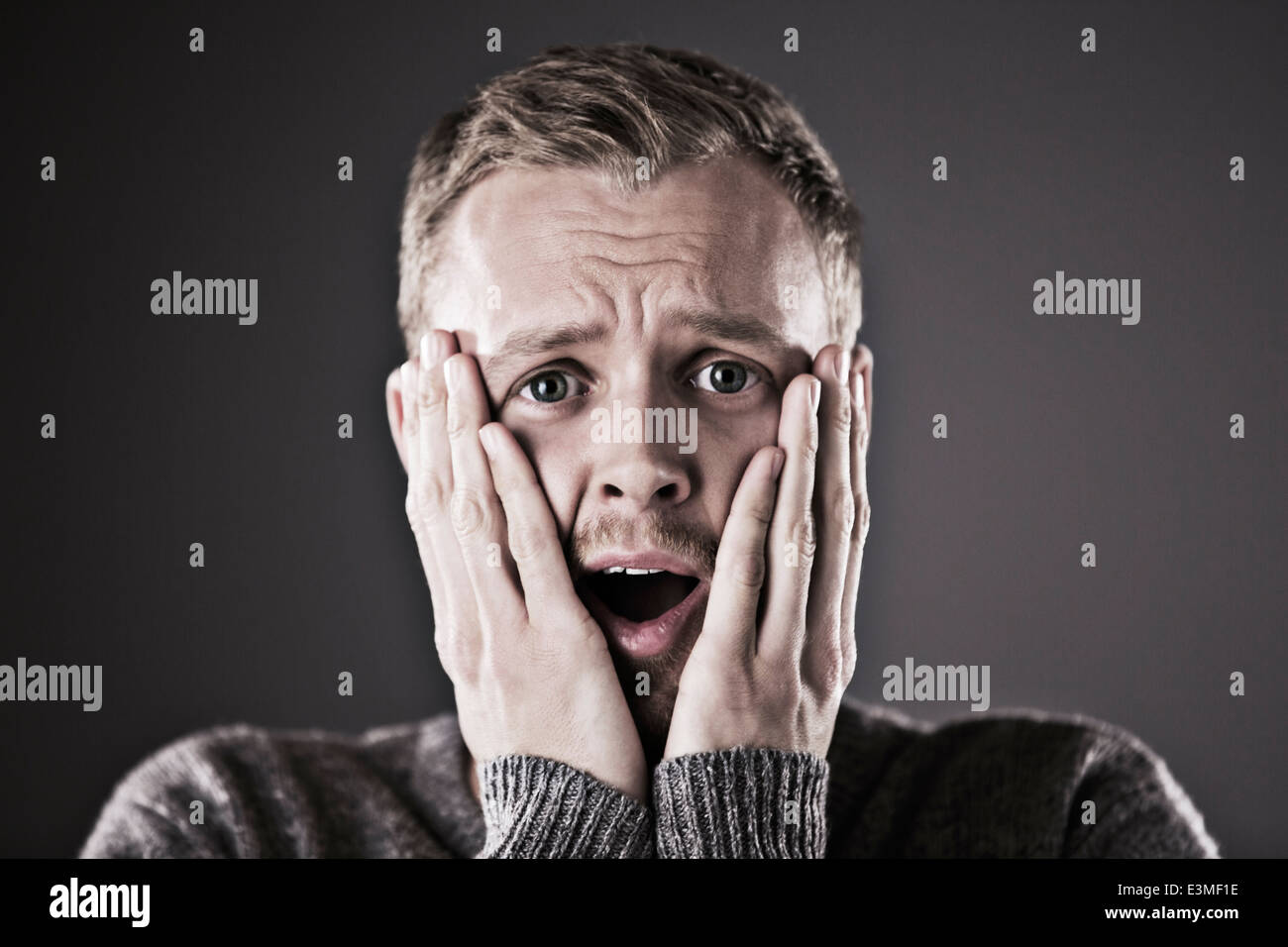 Portrait of surprised man with head in hands Stock Photo