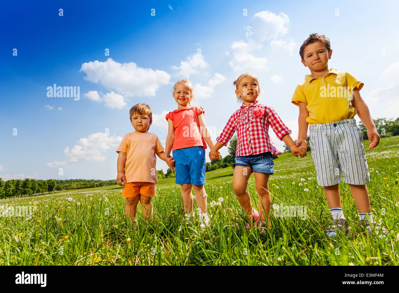 Four children holding hands and standing together Stock Photo