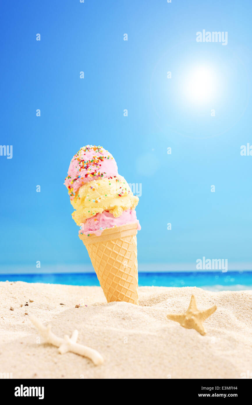 Ice cream stuck in sand on a sunny tropical beach with the sky in the