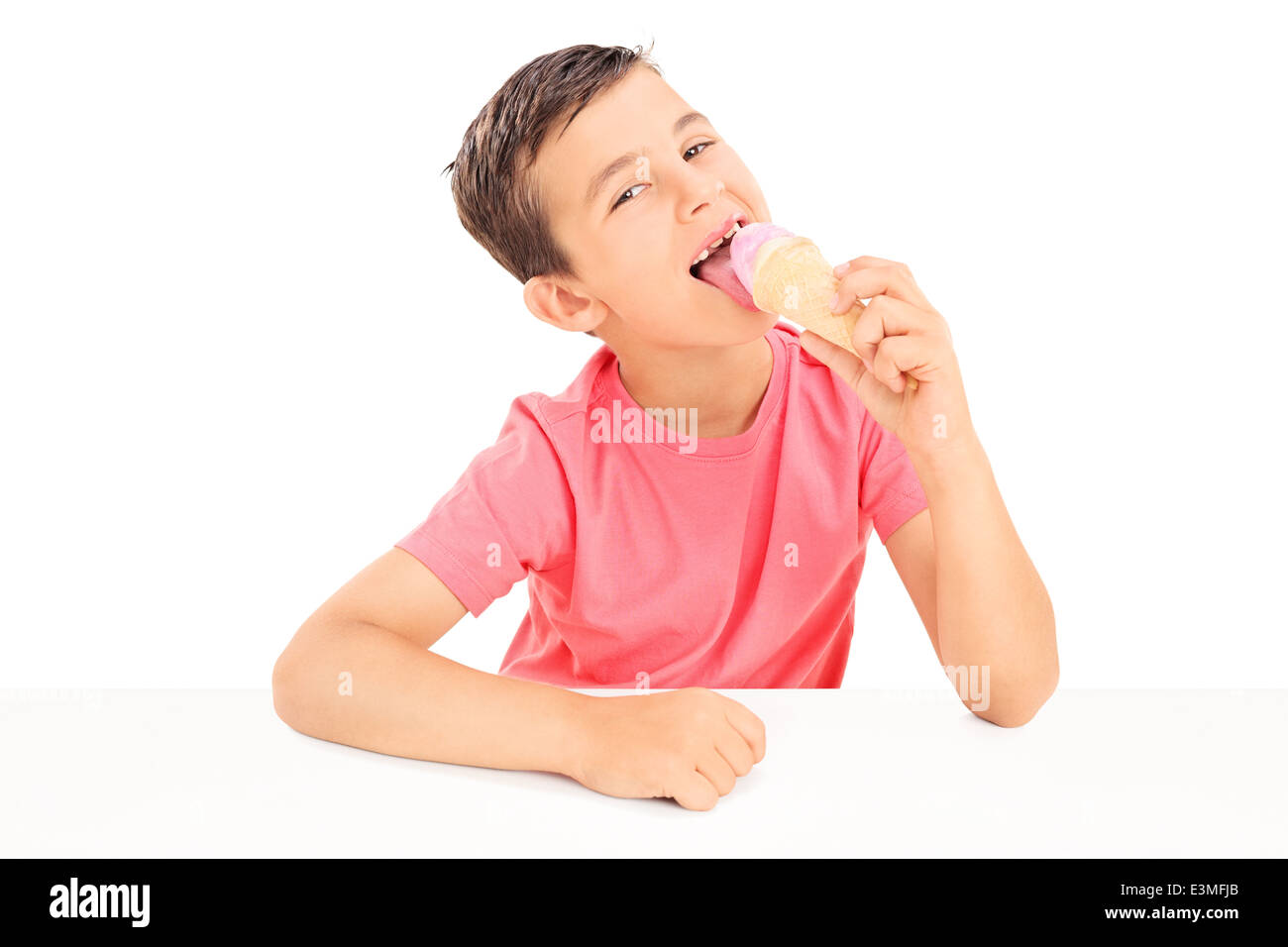 Joyful little boy eating an ice cream seated at a table Stock Photo