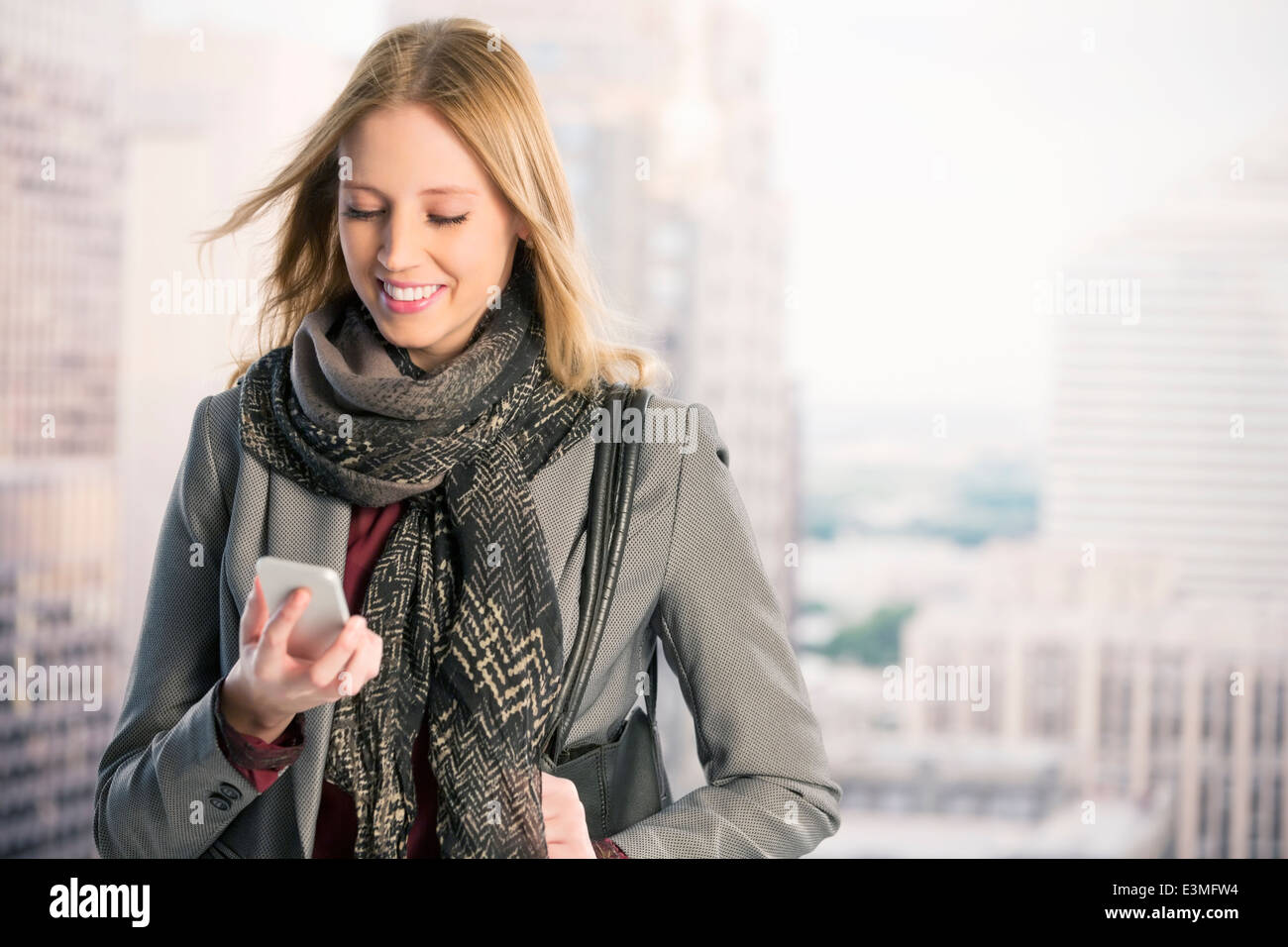 Smiling businesswoman using cell phone in urban window Stock Photo