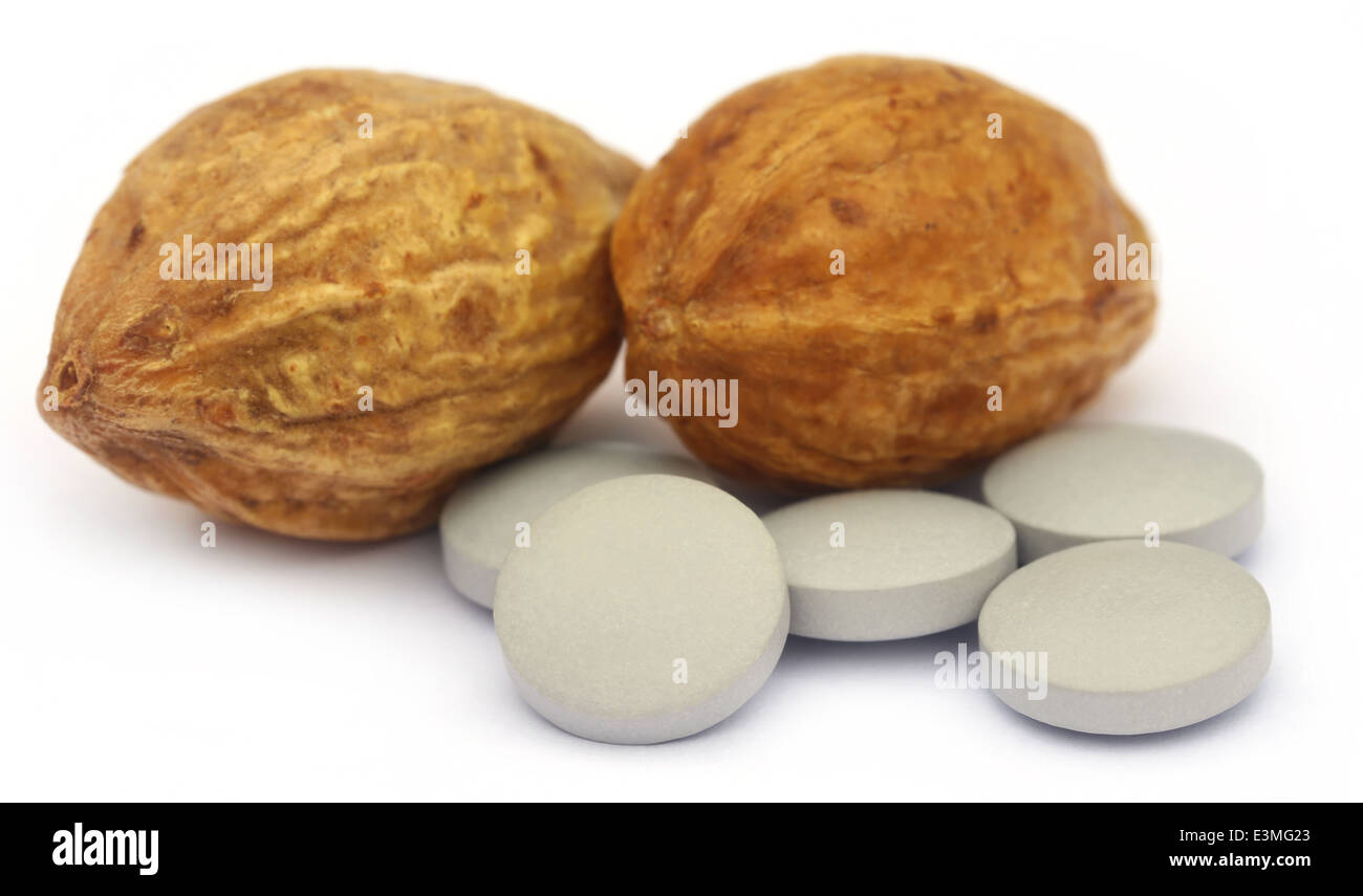 Medicinal Haritaki fruits with tablets over white background Stock Photo