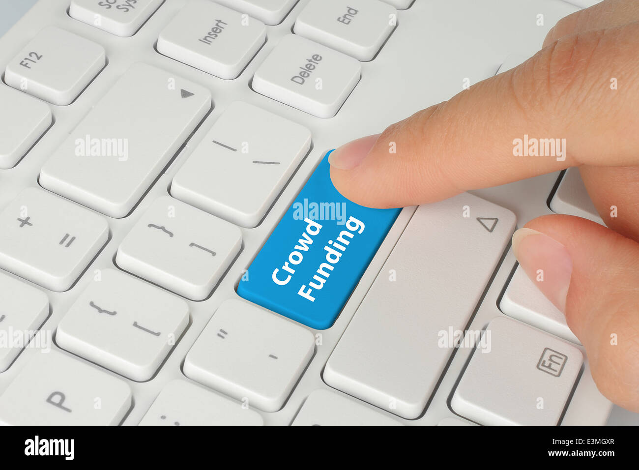 Hand pushing blue crowd funding button on keyboard Stock Photo