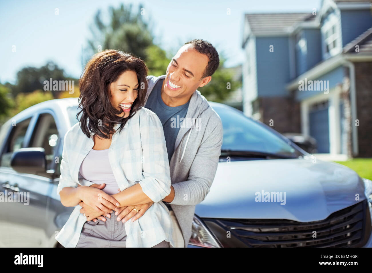 Happy couple hugging in driveway Stock Photo