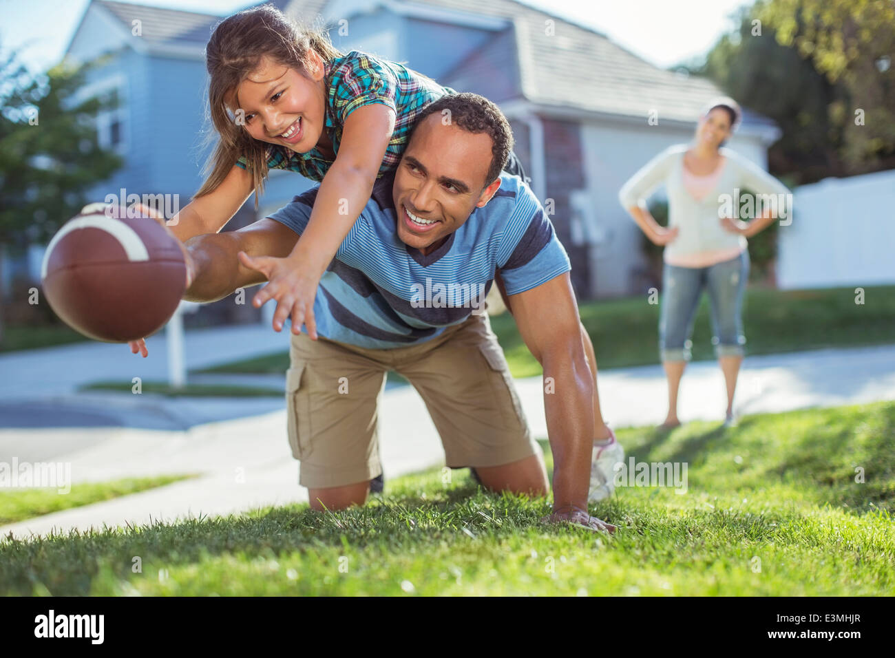 Father and daughter playing football in yard Stock Photo