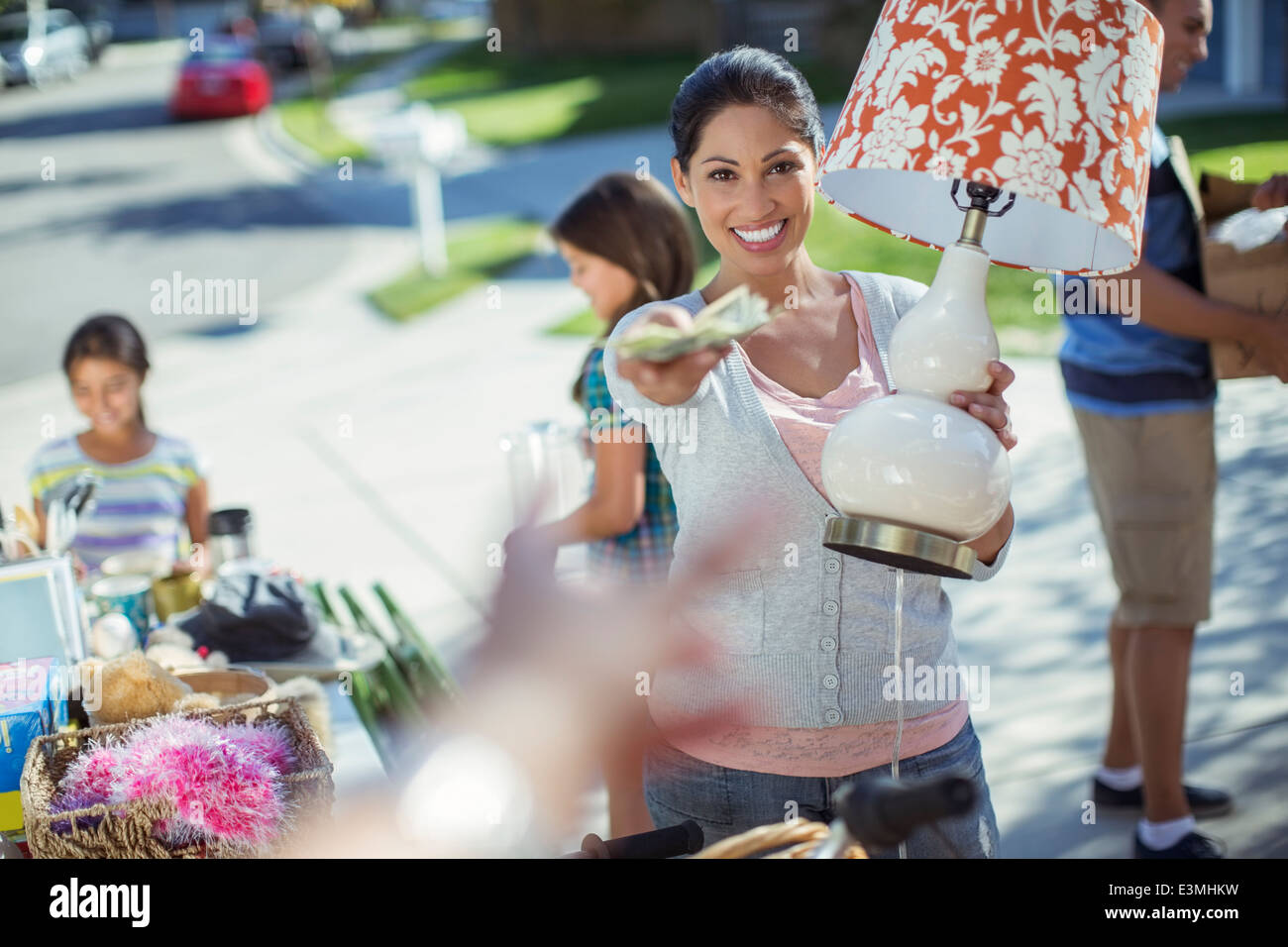 Portrait of woman paying for lamp at yard sale Stock Photo