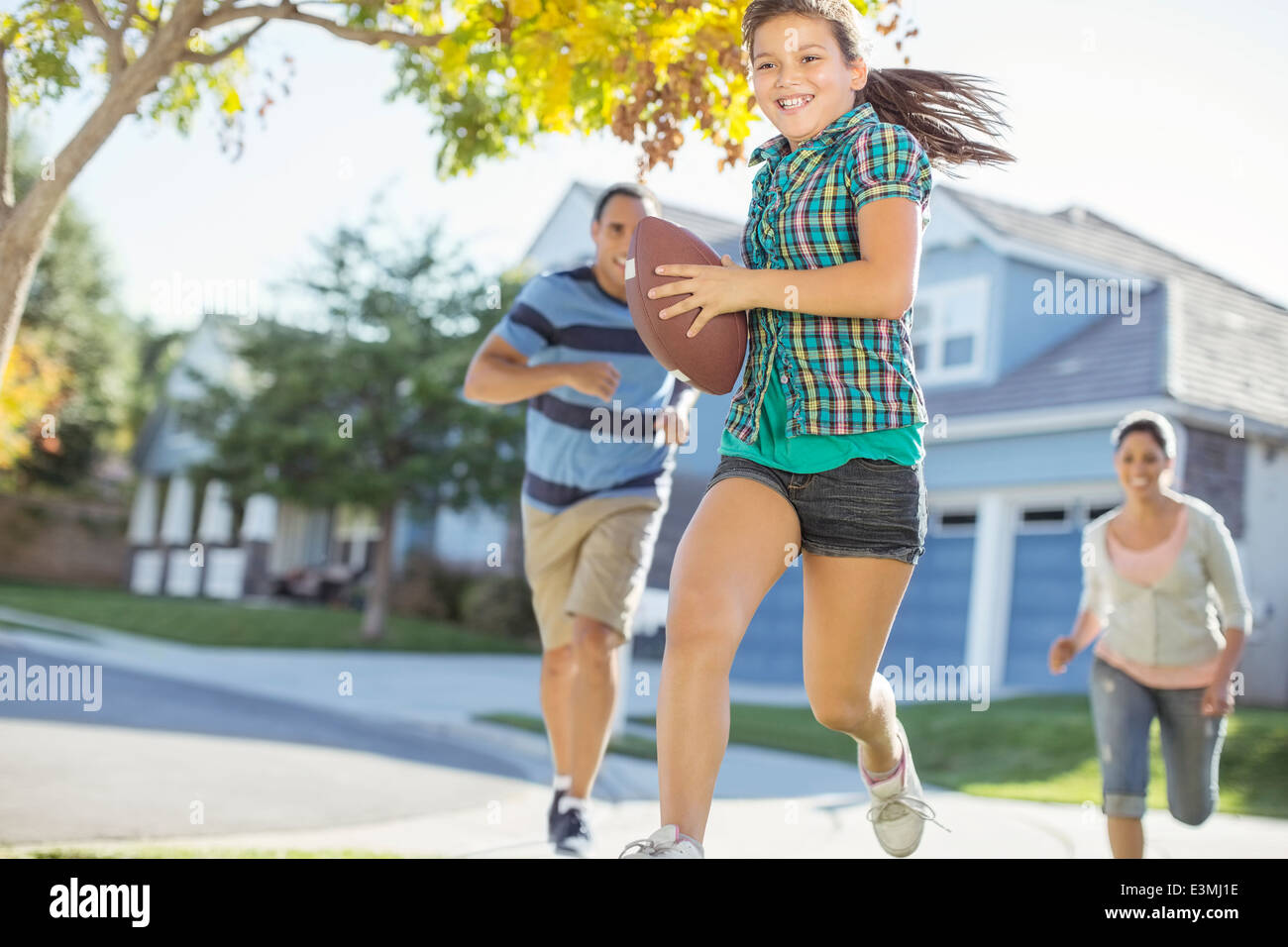 Family playing football in sunny street Stock Photo