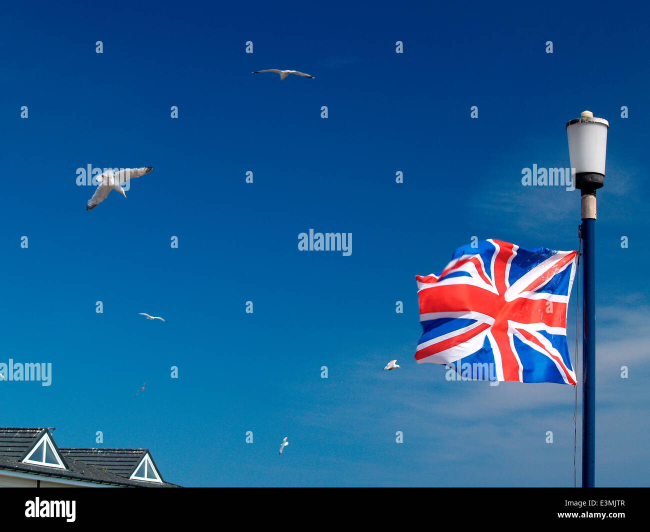 union flag blowing in the wind,gulls in flight & deep blue sky in summer Stock Photo