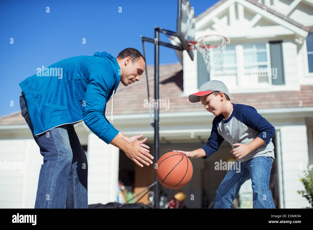 Father and son playing basketball in sunny driveway Stock Photo