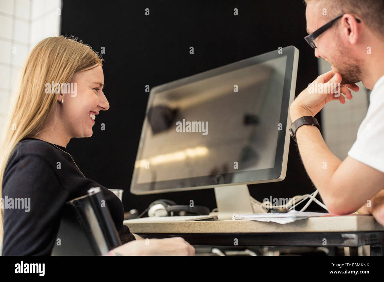 Young businessman and businesswoman looking at computer monitor in creative office Stock Photo