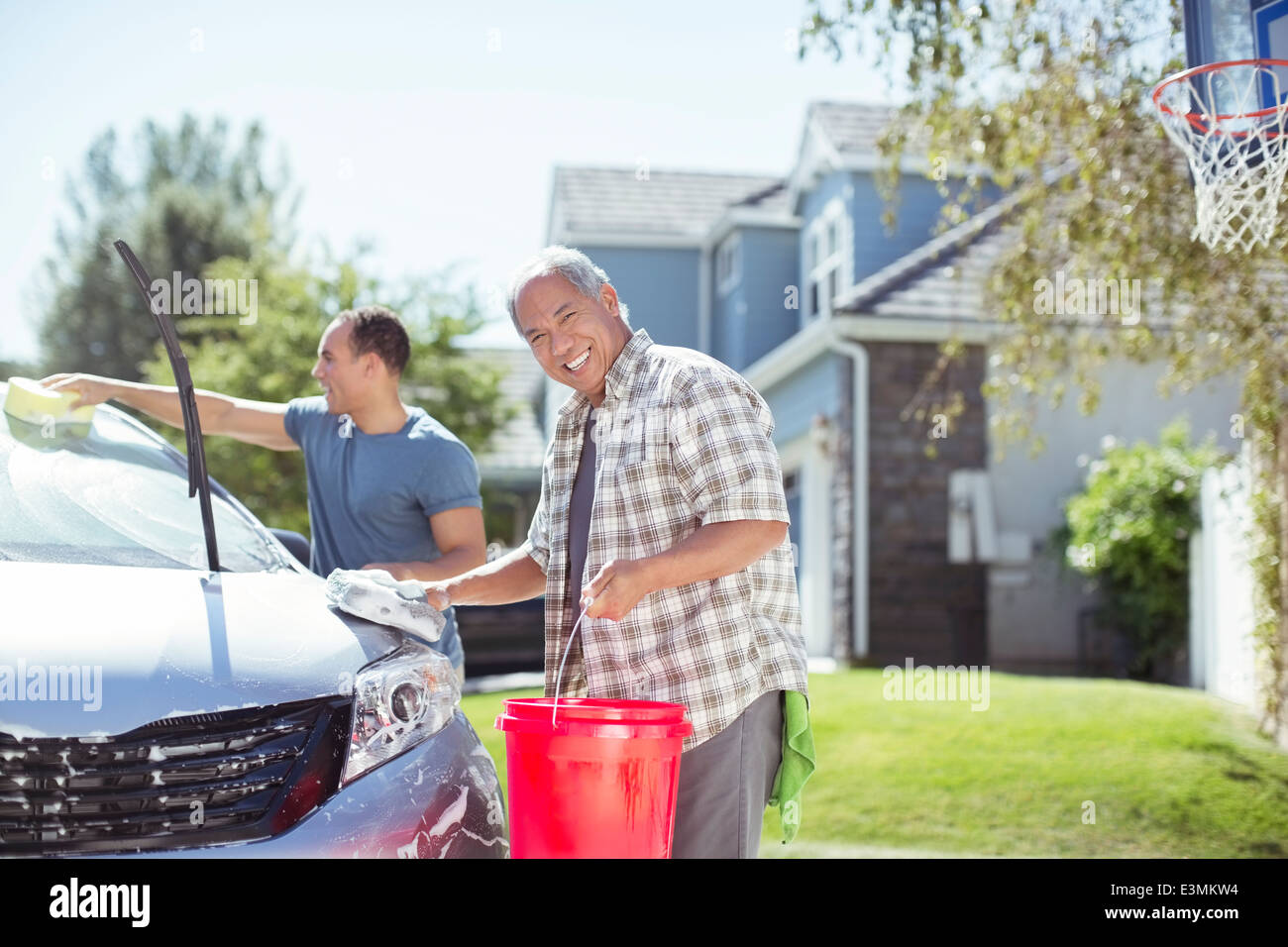 Portrait of smiling father and son washing car in driveway Stock Photo