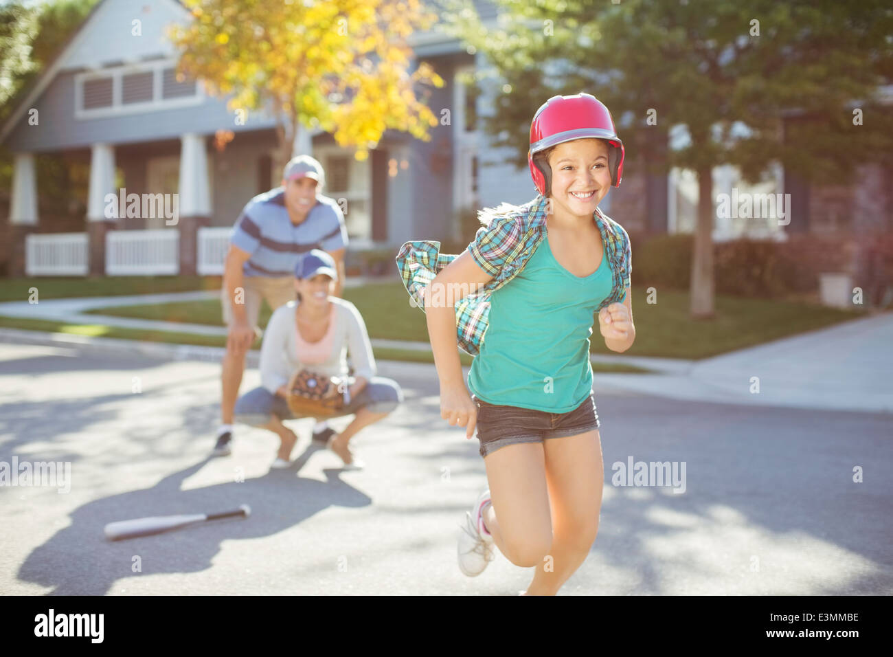 Family playing baseball in street Stock Photo