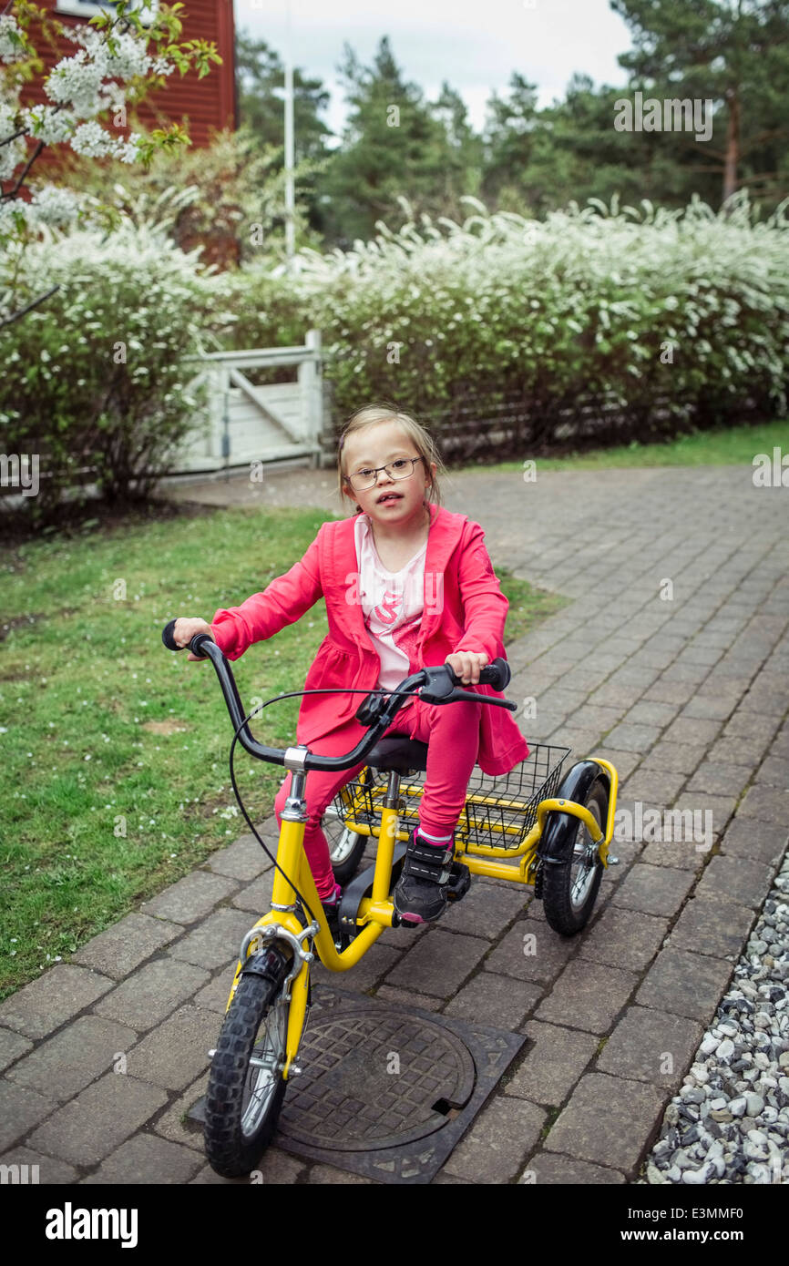 Portrait of girl with down syndrome riding bicycle in lawn Stock Photo