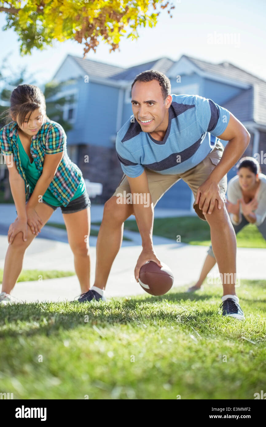 Family playing football in grass Stock Photo