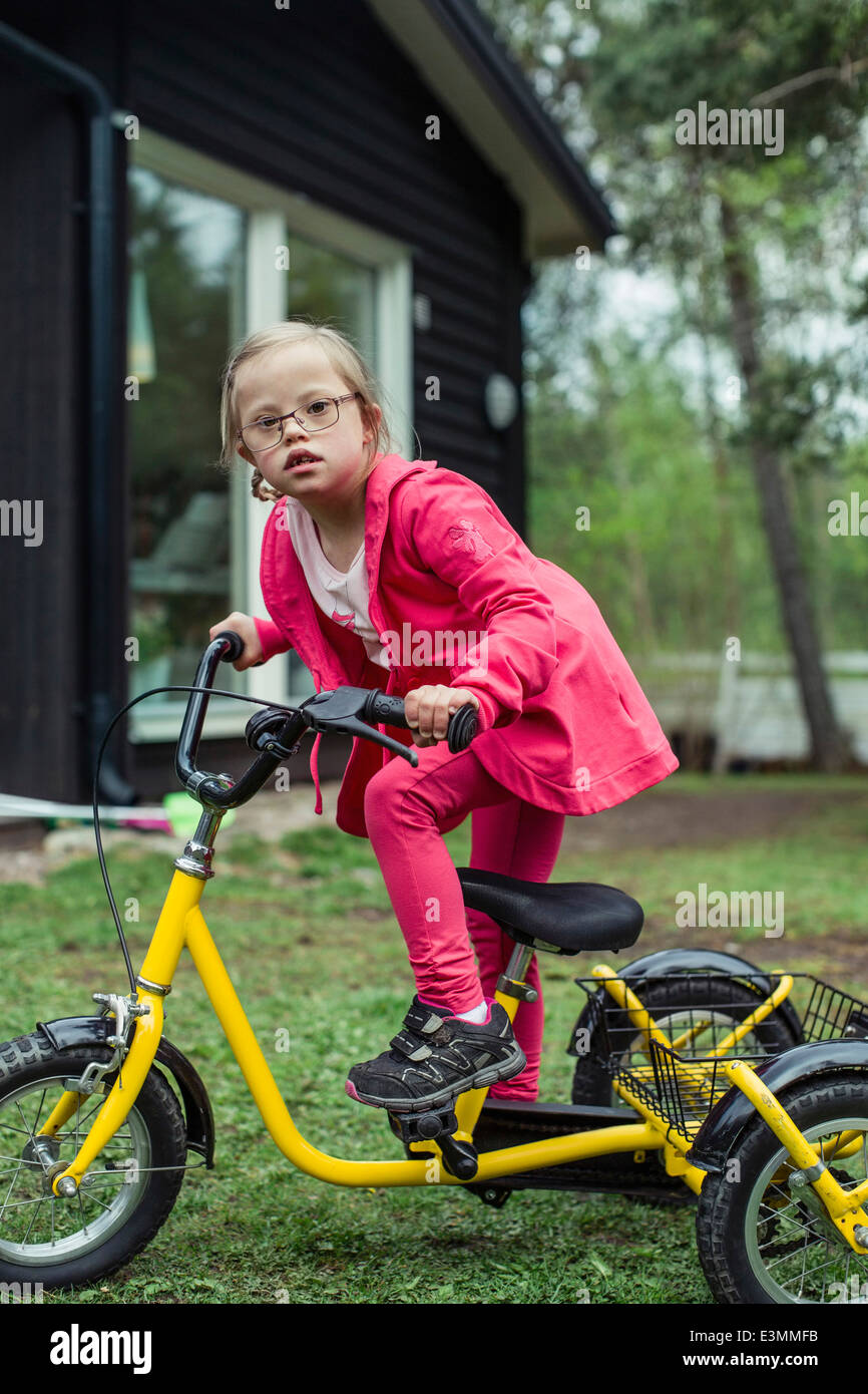 Portrait of girl with down syndrome riding bicycle in lawn Stock Photo