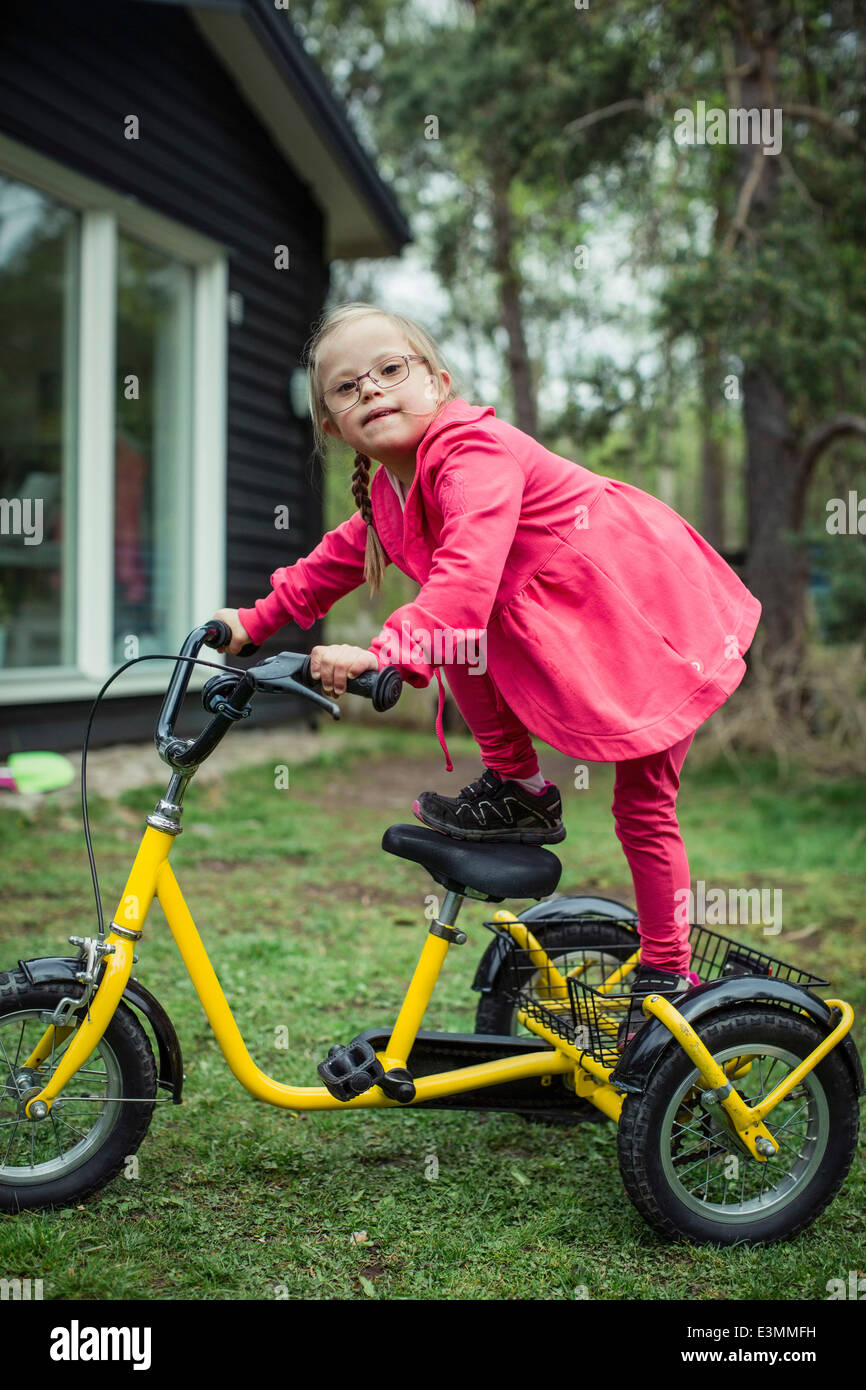 Portrait of girl with down syndrome balancing on bicycle in lawn Stock Photo