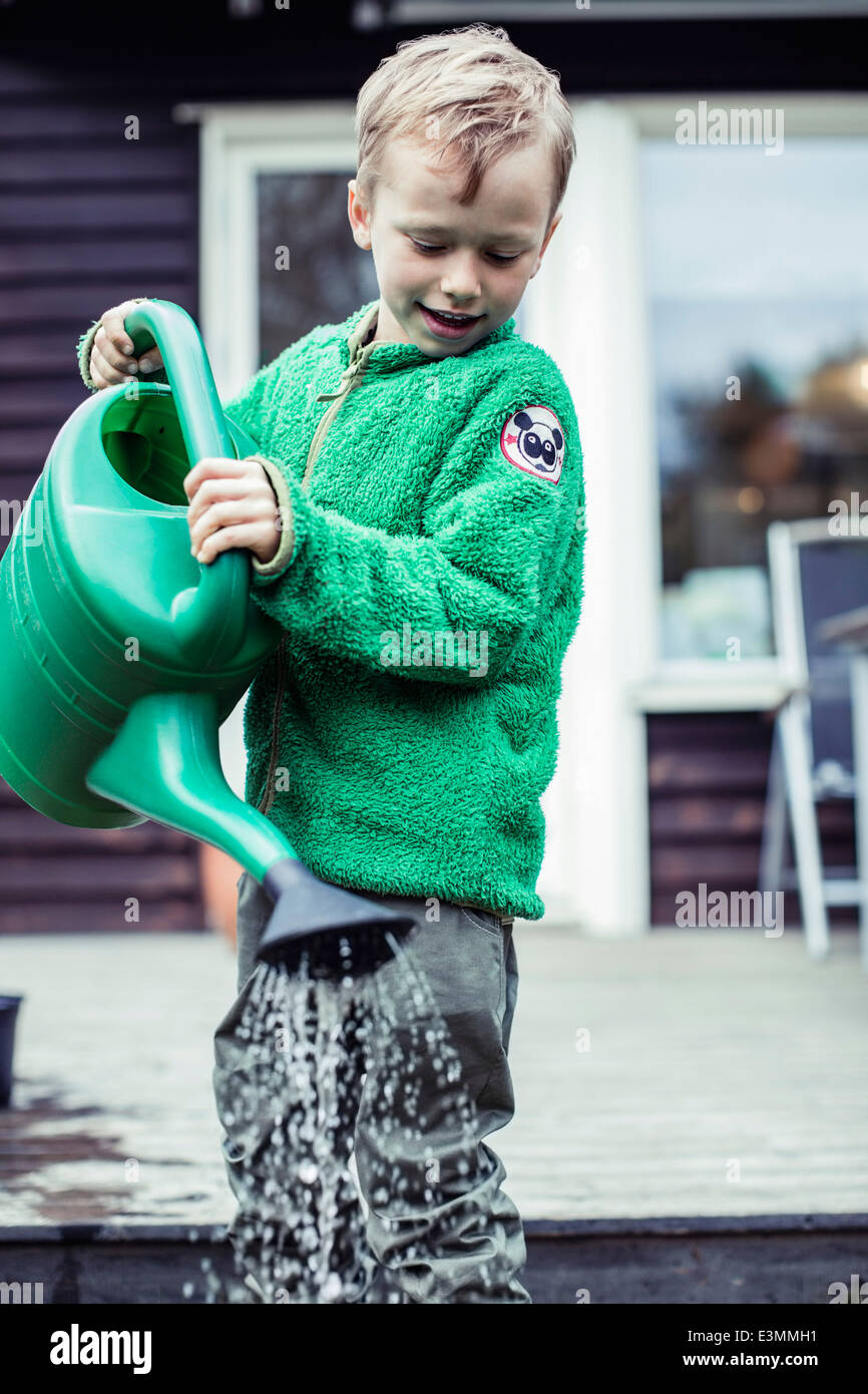 Boy using watering can in yard Stock Photo Alamy