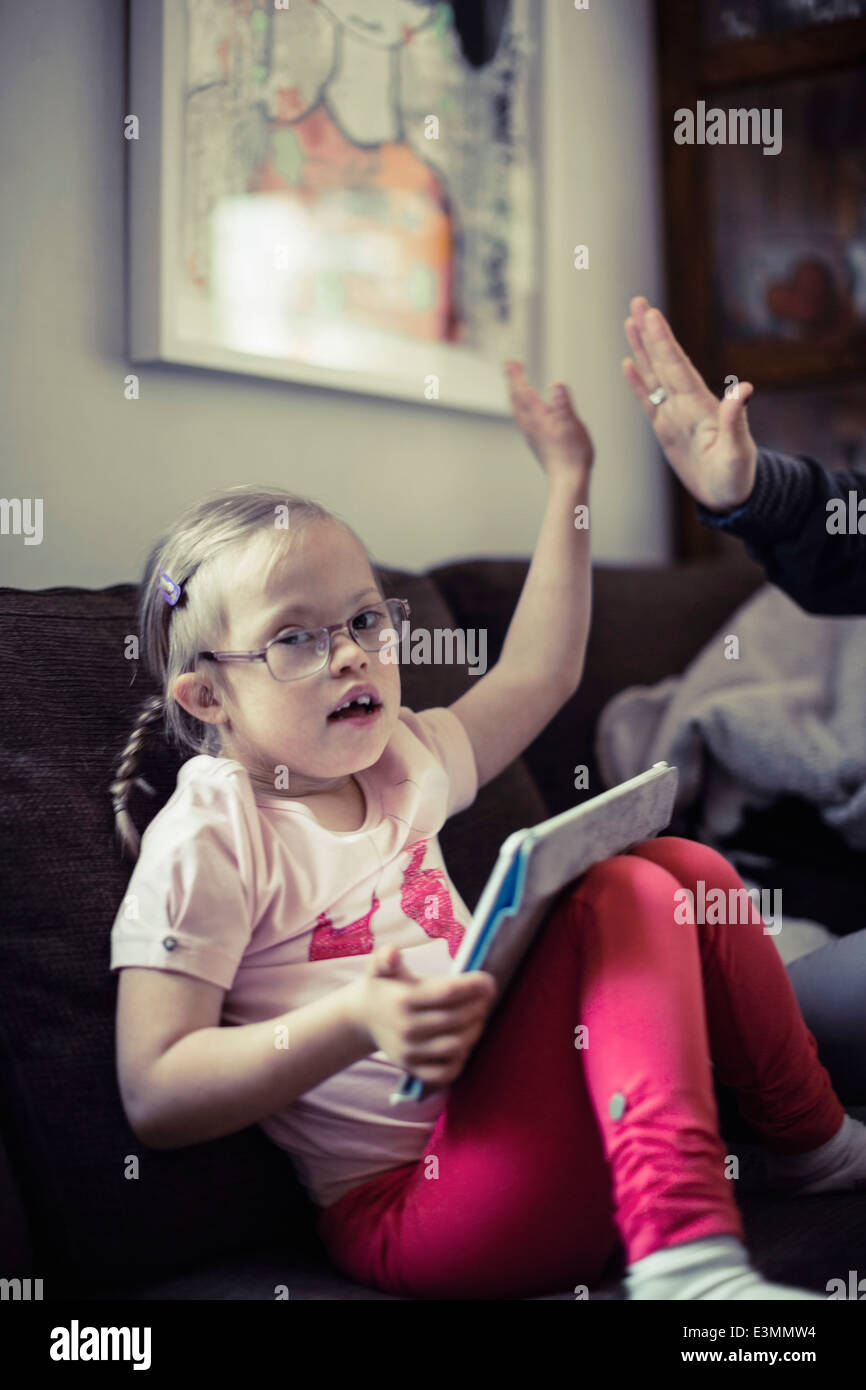 Portrait of girl giving high-five to mother on sofa Stock Photo