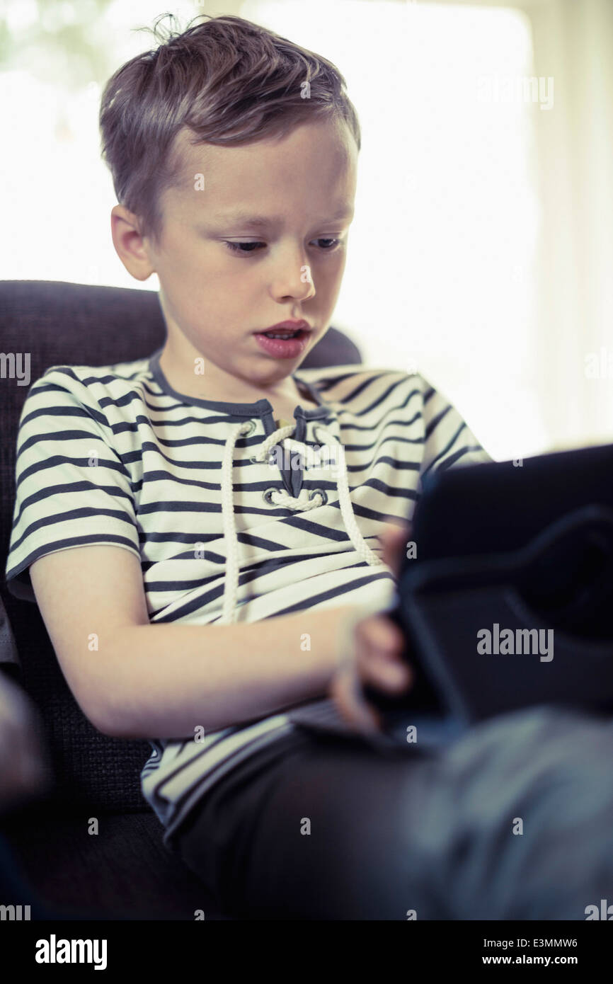 Boy using digital tablet on sofa Stock Photo