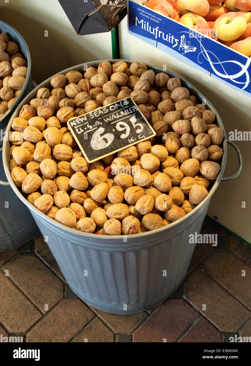 Dustbin full of walnuts for sale at market stall, Oxford, UK Stock
