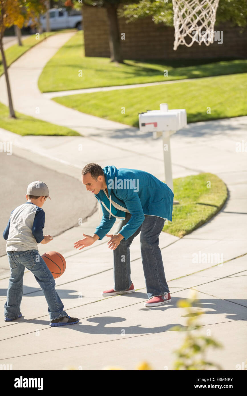 Father and son playing basketball in sunny driveway Stock Photo